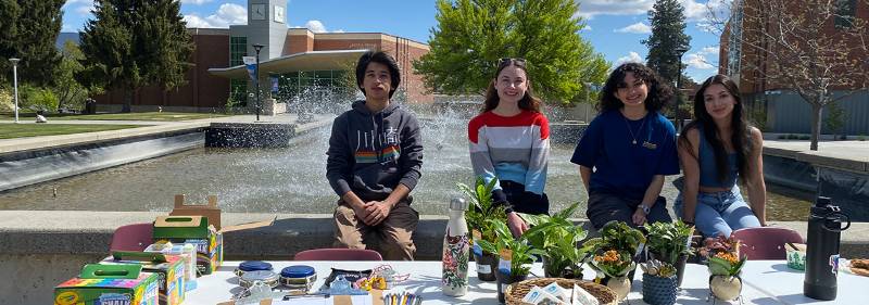 Student table at Earth Day 2024 Event Three students at table with plants.